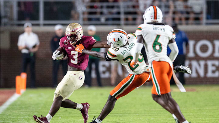 Florida State Seminoles running back Trey Benson (3) fends off a defender as he runs down the field. The Florida State Seminoles defeated the Miami Hurricanes 27-20 on Saturday, Nov. 11, 2023.