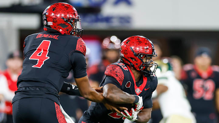 Oct 3, 2025; San Diego, California, USA; San Diego State Aztecs quarterback Jayden Denegal (4) hands the ball off to running back Christian Washington (23) during the first half against the Colorado State Rams at Snapdragon Stadium. Oct 3, 2025; San Diego, California, USA; San Diego State Aztecs quarterback Jayden Denegal (4) hands the ball off to running back Christian Washington (23) during the first half against the Colorado State Rams at Snapdragon Stadium.