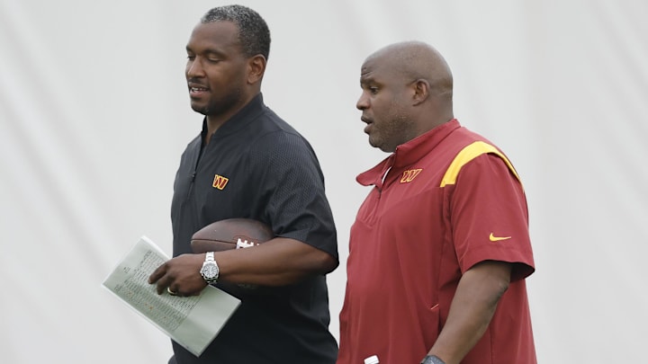 Washington Commanders wide receivers coach Bobby Engram (L) talks with Commanders assistant head coach/offensive coordinator Eric Bieniemy (R) 
