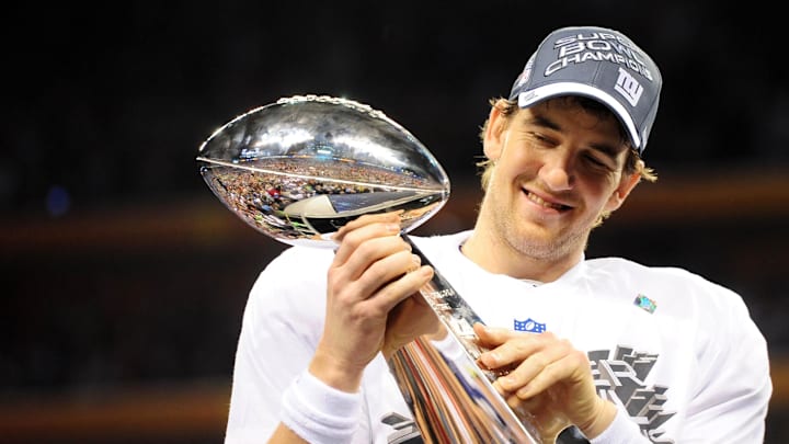 CAPTION: Feb 5, 2012; Indianapolis, IN, USA; New York Giants quarterback Eli Manning holds the Vince Lombardi Trophy after the Giants defeated the New England Patriots 21-17 in Super Bowl XLVI at Lucas Oil Stadium.  