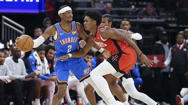 Dec 1, 2024; Houston, Texas, USA; Oklahoma City Thunder guard Shai Gilgeous-Alexander (2) controls the ball as Houston Rockets forward Amen Thompson (1) defends during the game at Toyota Center. Mandatory Credit: Troy Taormina-Imagn Images
