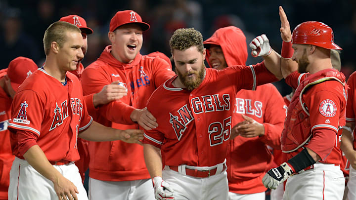 Angels first baseman Jared Walsh (25) is greeted by catcher Jonathan Lucroy (20) and catcher Dustin Garneau (13) and starting pitcher Trevor Cahill (53) after hitting a walk off RBI single against the Texas Rangers at Angel Stadium of Anaheim on May 25, 2019.