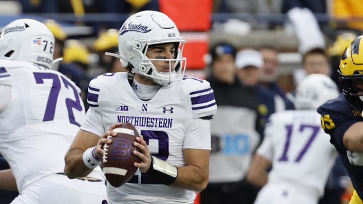 Nov 23, 2024; Ann Arbor, Michigan, USA;  Northwestern Wildcats quarterback Jack Lausch (12) drops back to pass against the Michigan Wolverines in the first half at Michigan Stadium. Mandatory Credit: Rick Osentoski-Imagn Images