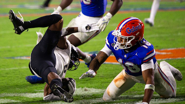 Florida Gators defensive back Bryce Thornton (18) upends UCF Knights running back RJ Harvey (7) during the second half at Ben Hill Griffin Stadium in Gainesville, FL on Saturday, October 5, 2024. [Doug Engle/Gainesville Sun]