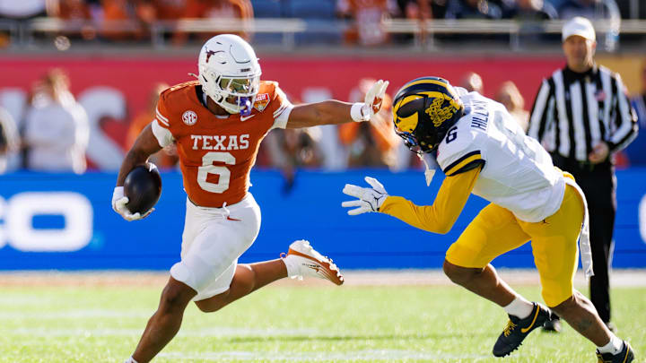 Dec 31, 2025; Orlando, FL, USA; Texas Longhorns running back Christian Clark (6) stiff arms Michigan Wolverines defensive back Brandyn Hillman (6) during the first half at Camping World Stadium.