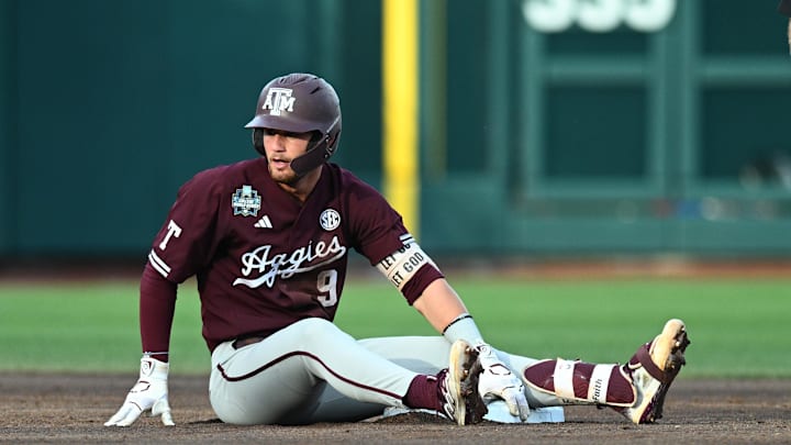 Jun 19, 2024; Omaha, NE, USA;  Texas A&M Aggies third baseman Gavin Grahovac (9) sits on the base after being thrown out against the Florida Gators during the second inning at Charles Schwab Field Omaha. Mandatory Credit: Steven Branscombe-Imagn Images