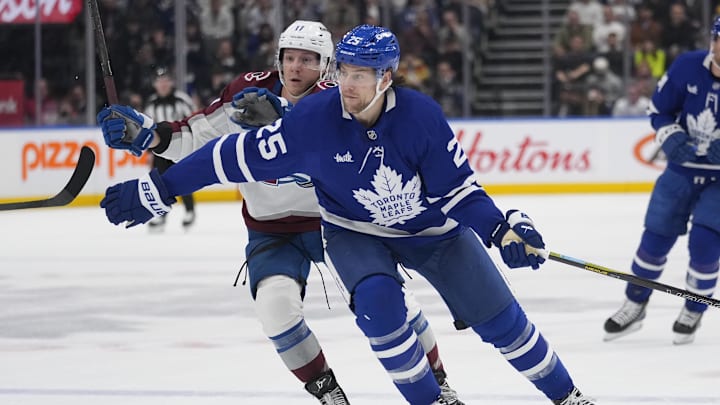 Mar 19, 2025; Toronto, Ontario, CAN; Toronto Maple Leafs defenceman Brandon Carlo (25) tries to slow up Colorado Avalanche forward Brock Nelson (11) during the first period at Scotiabank Arena. Mandatory Credit: John E. Sokolowski-Imagn Images