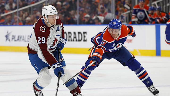 Feb 7, 2025; Edmonton, Alberta, CAN; Edmonton Oilers forward Mattias Janmark (13) tries to knock the puck away from Colorado Avalanche forward Nathan MacKinnon (29) during the second period at Rogers Place. Mandatory Credit: Perry Nelson-Imagn Images