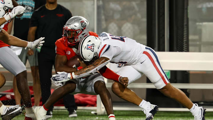Aug 31, 2024; Tucson, Arizona, USA; New Mexico quarterback Devon Dampier (4) gets tackled by Arizona Wildcats defensive back Dalton Johnson (43) during fourth quarter at Arizona Stadium. Mandatory Credit: Aryanna Frank-Imagn Images