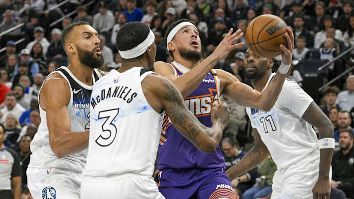 Nov 17, 2024; Minneapolis, Minnesota, USA; Phoenix Suns guard Devin Booker (1) cuts through Minnesota Timberwolves center Rudy Gobert (27), forward Jaden McDaniels (3), and center Naz Reid (11) for a layup during the second quarter at Target Center. Mandatory Credit: Nick Wosika-Imagn Images