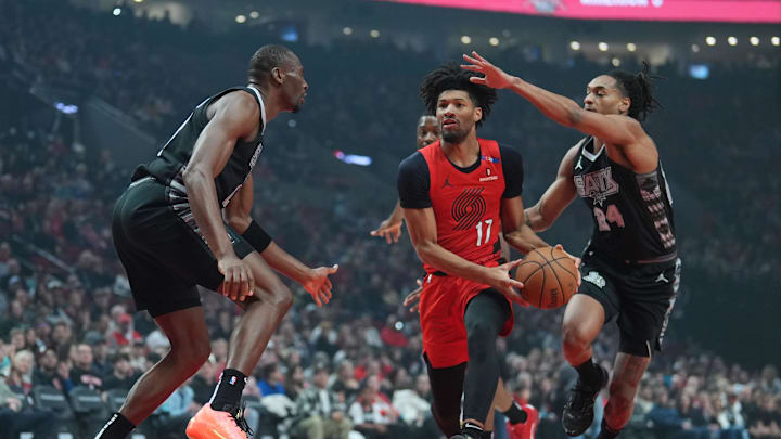 Apr 6, 2025; Portland, Oregon, USA; Portland Trail Blazers shooting guard Shaedon Sharpe (17) drives for the basket between San Antonio Spurs center Bismack Biyombo (18) and shooting guard Devin Vassell (24) during the first half at Moda Center. Mandatory Credit: Soobum Im-Imagn Images Apr 6, 2025; Portland, Oregon, USA; Portland Trail Blazers shooting guard Shaedon Sharpe (17) drives for the basket between San Antonio Spurs center Bismack Biyombo (18) and shooting guard Devin Vassell (24) during the first half at Moda Center. Mandatory Credit: Soobum Im-Imagn Images