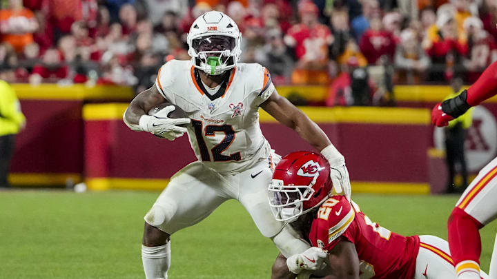 Dec 25, 2025; Kansas City, Missouri, USA; Denver Broncos running back RJ Harvey (12) runs the ball as Kansas City Chiefs cornerback Nohl Williams (20) makes the tackle during the third quarter at GEHA Field at Arrowhead Stadium. Mandatory Credit: Denny Medley-Imagn Images