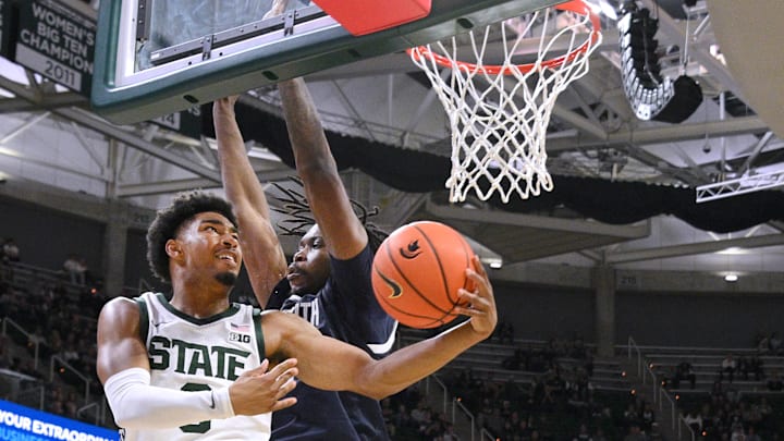 Nov 4, 2024; East Lansing, Michigan, USA; Michigan State Spartans guard Jaden Akins (3) puts up a reverse layup against Monmouth Hawks guard Abdi Bashir Jr. (1) during the second half at Jack Breslin Student Events Center. Mandatory Credit: Dale Young-Imagn Images