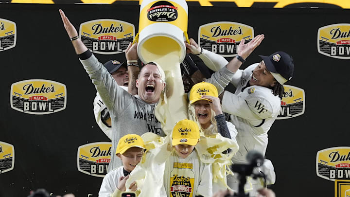 Jan 2, 2026; Charlotte, NC, USA;  Wake Forest Demon Deacons defensive back Nick Andersen (45) and Wake Forest Demon Deacons quarterback Robby Ashford (2) dump mayo on  head coach Jake Dickert and his family receive the traditional mayo dump after Wake Forest Demon Deacons win at Bank of America Stadium. Mandatory Credit: Jim Dedmon-Imagn Images