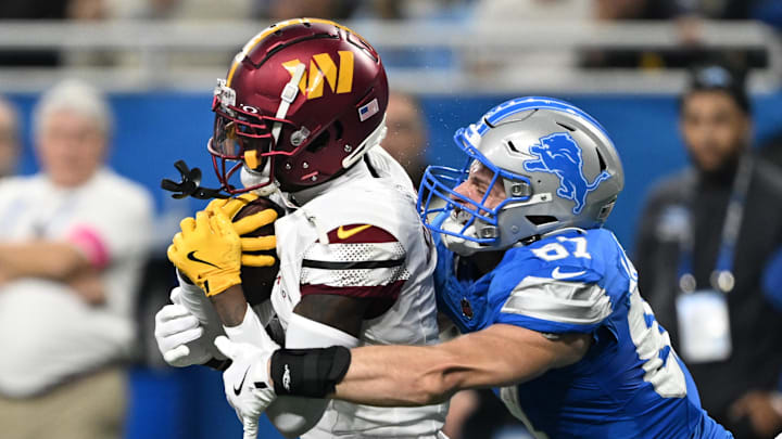 Detroit Lions tight end Sam LaPorta (87) tackles Washington Commanders cornerback Mike Sainristil (0) after intercepting a pass during the second quarter in a 2025 NFC divisional round game at Ford Field.