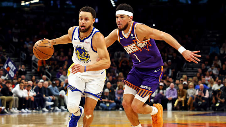 Golden State Warriors guard Stephen Curry (30) drives to the basket against Phoenix Suns guard Devin Booker (1) during the fourth quarter at Footprint Center. Mandatory Credit: Mark J. Rebilas-Imagn Images