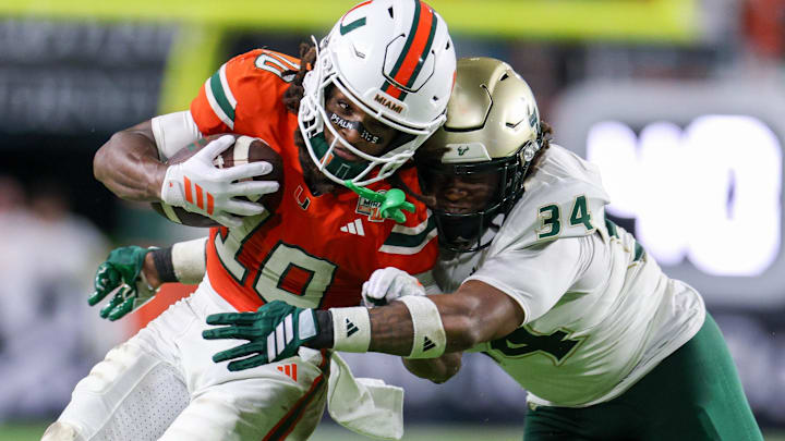 Sep 13, 2025; Miami Gardens, Florida, USA; Miami Hurricanes tight end Brock Schott (19) is tackled by South Florida Bulls fullback Rico Watson III (34) in the third quarter at Hard Rock Stadium. Mandatory Credit: Nathan Ray Seebeck-Imagn Images