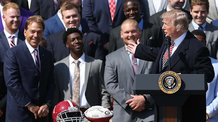 Apr 10, 2018; Washington, DC, USA; President Donald Trump gestures as Alabama Crimson Tide head coach Nick Saban (L) smiles at a ceremony honoring the college football playoff champion Crimson Tide on the South Lawn at the White House. Mandatory Credit: Geoff Burke-Imagn Images