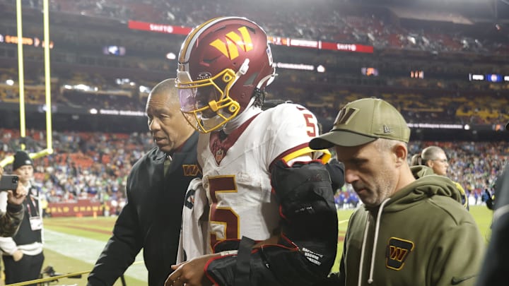 Washington Commanders quarterback Jayden Daniels is helped off the field after an injury.