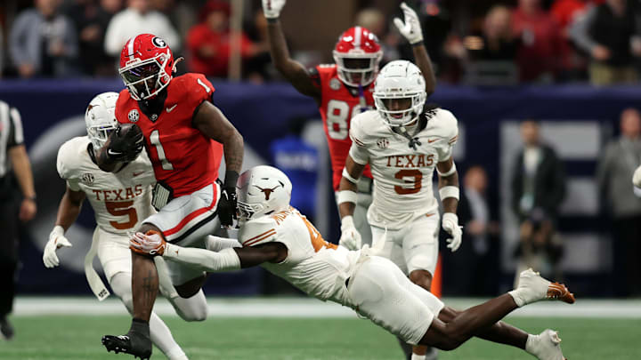 Dec 7, 2024; Atlanta, GA, USA; Georgia Bulldogs running back Trevor Etienne (1) rushes the ball against Texas Longhorns defensive back Andrew Mukuba (4) during the second half in the 2024 SEC Championship game at Mercedes-Benz Stadium. Mandatory Credit: Brett Davis-Imagn Images