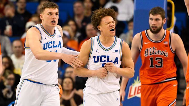 Feb 21, 2026; Los Angeles, California, USA; UCLA guard Trent Perry (0) reacts to scoring against Illinois during the second half while UCLA forward Tyler Bilodeau (34) (left) and Illinois center Tomislav Ivisic (13) (right) look on at Pauley Pavilion presented by Wescom Financial. Mandatory Credit: Robert Hanashiro-Imagn Images