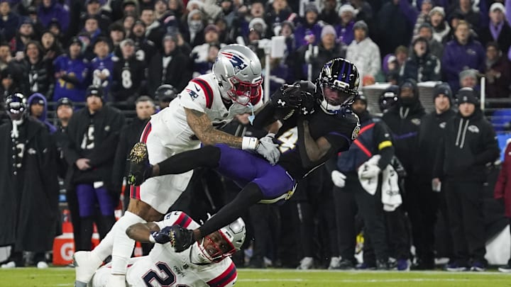 Dec 21, 2025; Baltimore, Maryland, USA;  Baltimore Ravens wide receiver Zay Flowers (4) is hit by New England Patriots cornerback Christian Gonzalez (0) during the first quarter of the game at M&T Bank Stadium. Mandatory Credit: James Lang-Imagn Images