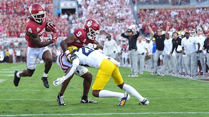 Oklahoma's Deion Burks (4) runs for a touchdown as Keontez Lewis (9) blocks Michigan's Jyaire Hill (20) in the first of the college football game between the University of Oklahoma Sooner and the University of Michigan Wolverines at the Gaylord Family Ð Oklahoma Memorial Stadium in Norman, Okla., Saturday, Sept. 6, 2025.