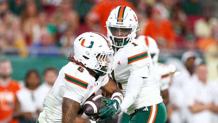 Sep 21, 2024; Tampa, Florida, USA; Miami Hurricanes quarterback Cam Ward (1) hands off to running back Damien Martinez (6) against the South Florida Bulls in the second quarter at Raymond James Stadium. Mandatory Credit: Nathan Ray Seebeck-Imagn Images