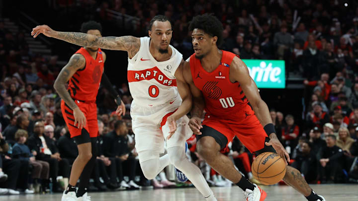Mar 16, 2025; Portland, Oregon, USA;  Portland Trail Blazers guard Scoot Henderson (00) dribbles the ball past Toronto Raptors guard A.J. Lawson (0) in the second half at Moda Center. Mandatory Credit: Jaime Valdez-Imagn Images