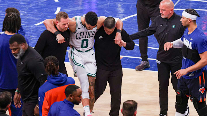 May 12, 2025; New York, New York, USA; Boston Celtics forward Jayson Tatum (0) is helped off the court by after an injury in the second half during game four of the second round for the 2025 NBA Playoffs against the New York Knicks at Madison Square Garden. Tatum would leave the game with an injury after this play. Mandatory Credit: Vincent Carchietta-Imagn Images