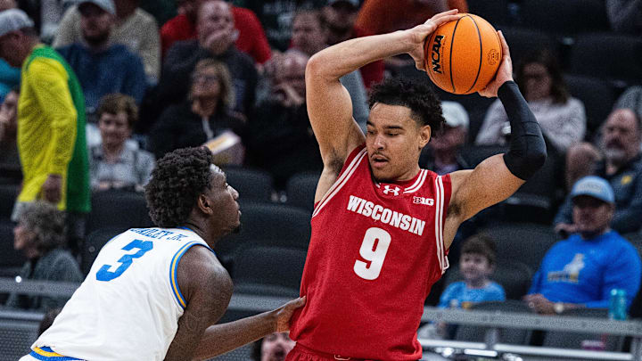 Mar 14, 2025; Indianapolis, IN, USA; Wisconsin Badgers guard John Tonje (9) holds  the ball while UCLA Bruins guard Eric Dailey Jr. (3) defends in the first half at Gainbridge Fieldhouse. Mandatory Credit: Trevor Ruszkowski-Imagn Images