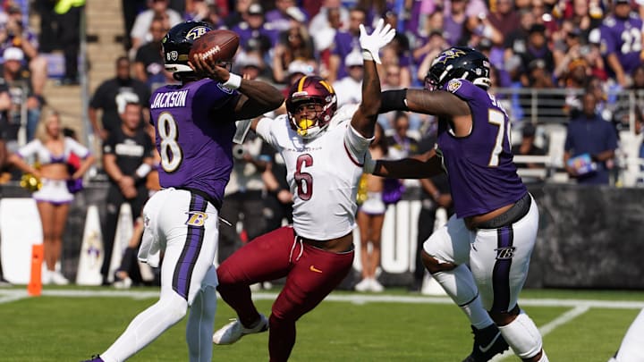 Oct 13, 2024; Baltimore, Maryland, USA; Baltimore Ravens quarterback Lamar Jackson (8) passes under pressure from Washington Commanders linebacker Dante Fowler Jr.(6) during the second quarter at M&T Bank Stadium. Mandatory Credit: Mitch Stringer-Imagn Images