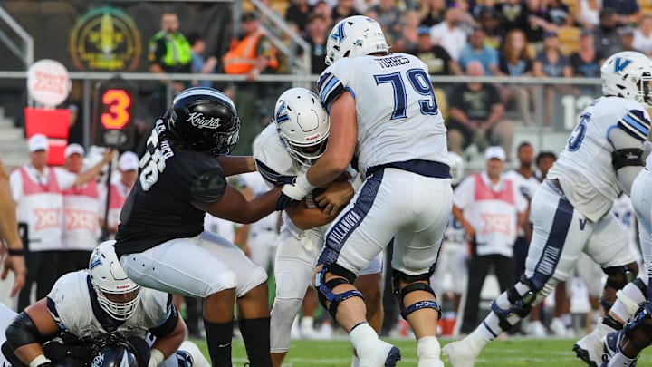 Sep 16, 2023; Orlando, Florida, USA; Villanova Wildcats quarterback Connor Watkins (4) is sacked by UCF Knights defensive tackle Matthew Alexander (56) during the first quarter at FBC Mortgage Stadium. Mandatory Credit: Mike Watters-Imagn Images