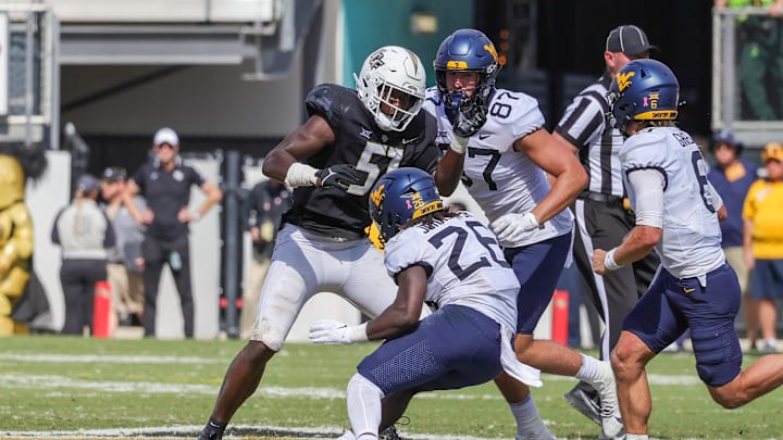 Oct 28, 2023; Orlando, Florida, USA; West Virginia Mountaineers running back Justin Johnson Jr. (26) is tackled by UCF Knights defensive end Malachi Lawrence (51) during the second half at FBC Mortgage Stadium. Mandatory Credit: Mike Watters-Imagn Images
