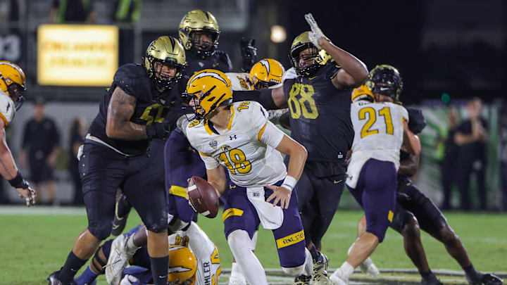 Aug 31, 2023; Orlando, Florida, USA; Kent State Golden Flashes quarterback Michael Alaimo (18) moves out to pass as UCF Knights defensive end Josh Celiscar (88) and defensive tackle John Walker (55) move in during the second half at FBC Mortgage Stadium. Mandatory Credit: Mike Watters-Imagn Images battle for the ball