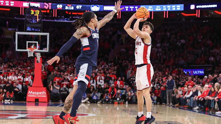 Feb 6, 2026; New York, New York, USA;  St. John's basketball guard Dylan Darling (0) takes a three point shot past UConn Huskies guard Solo Ball (1) in the second half at Madison Square Garden.