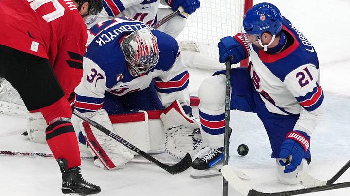 Feb 22, 2026; Milan, Italy; Connor Hellebuyck and Dylan Larkin of the United States reach for a loose puck against Nick Suzuki of Canada during the men's ice hockey gold medal game during the Milano Cortina 2026 Olympic Winter Games at Milano Santagiulia Ice Hockey Arena. Mandatory Credit: James Lang-Imagn Images
