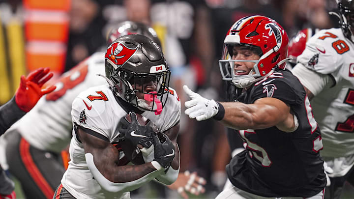 Oct 3, 2024; Atlanta, Georgia, USA; Tampa Bay Buccaneers running back Bucky Irving (7) runs against Atlanta Falcons linebacker Kaden Elliss (55) during the first half at Mercedes-Benz Stadium. Mandatory Credit: Dale Zanine-Imagn Images