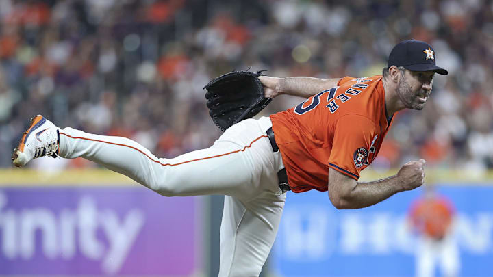 Former Houston Astros pitcher Justin Verlander throws a pitch wearing an orange jersey and navy blue hat. Former Houston Astros pitcher Justin Verlander throws a pitch wearing an orange jersey and navy blue hat.