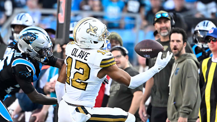 Nov 9, 2025; Charlotte, North Carolina, USA;  New Orleans Saints wide receiver Chris Olave (12) makes a one handed catch as Carolina Panthers cornerback Chau Smith-Wade (26) defends in the fourth quarter at Bank of America Stadium. Mandatory Credit: Bob Donnan-Imagn Images