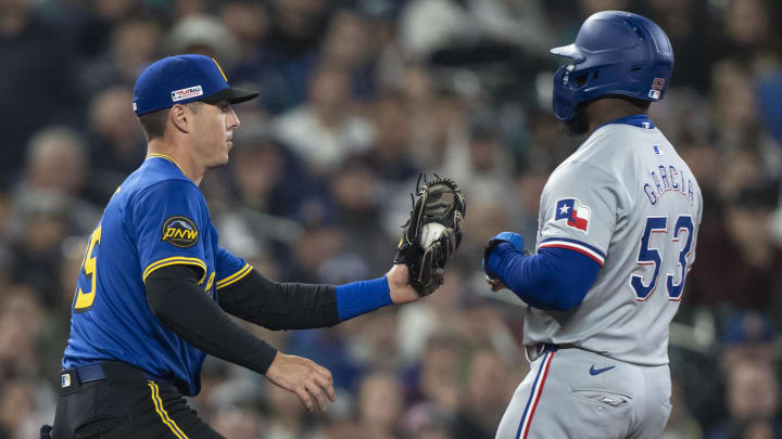 Jun 14, 2024; Seattle, Washington, USA; Seattle Mariners third baseman Dylan Moore (25) tags out Texas Rangers right fielder Adolis Garcia (53) during the sixth inning at T-Mobile Park. Mandatory Credit: Stephen Brashear-USA TODAY Sports