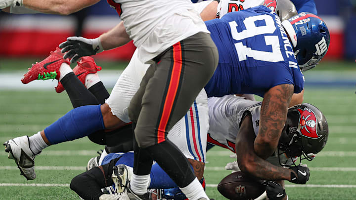 Nov 24, 2024; East Rutherford, New Jersey, USA; Tampa Bay Buccaneers running back Bucky Irving (7) fumbles the ball as New York Giants defensive tackle Dexter Lawrence II (97) tackles during the second half at MetLife Stadium.  