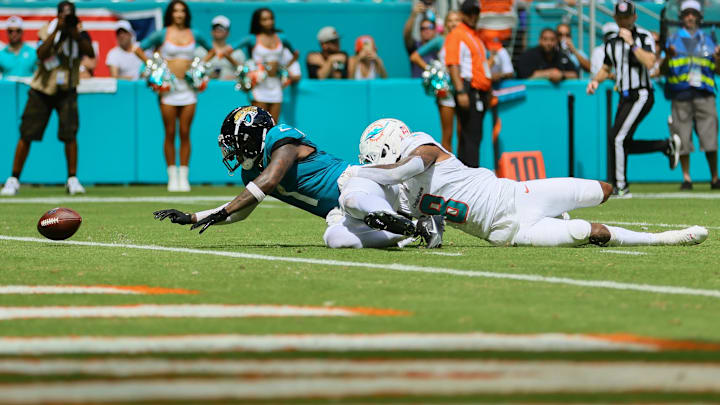 Sep 8, 2024; Miami Gardens, Florida, USA; Jacksonville Jaguars running back Travis Etienne Jr. (1) fumbles the football after a tackle from Miami Dolphins safety Jevon Holland (8) during the third quarter at Hard Rock Stadium. Mandatory Credit: Sam Navarro-Imagn Images