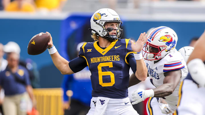 Sep 21, 2024; Morgantown, West Virginia, USA; West Virginia Mountaineers quarterback Garrett Greene (6) throws a pass and is rushed by Kansas Jayhawks linebacker JB Brown (1) during the first quarter at Mountaineer Field at Milan Puskar Stadium. Mandatory Credit: Ben Queen-Imagn Images