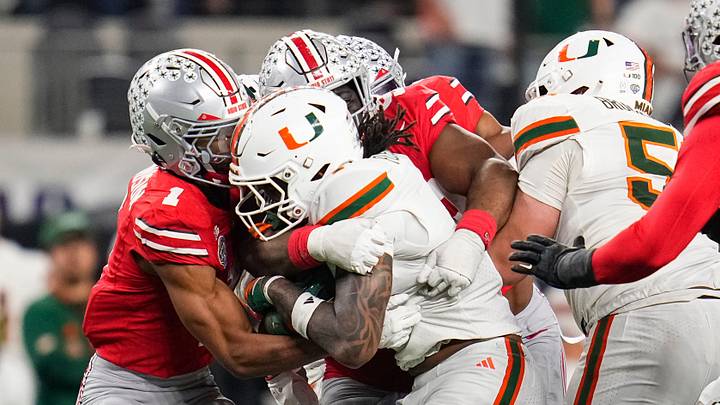 Ohio State Buckeyes cornerback Davison Igbinosun (1) and teammates stop Miami Hurricanes running back Mark Fletcher Jr. (4) during the Cotton Bowl at AT&T Stadium in Arlington, Texas for the College Football Playoff quarterfinal game on Dec. 31, 2025. Ohio State lost 24-14. Ohio State Buckeyes cornerback Davison Igbinosun (1) and teammates stop Miami Hurricanes running back Mark Fletcher Jr. (4) during the Cotton Bowl at AT&T Stadium in Arlington, Texas for the College Football Playoff quarterfinal game on Dec. 31, 2025. Ohio State lost 24-14.