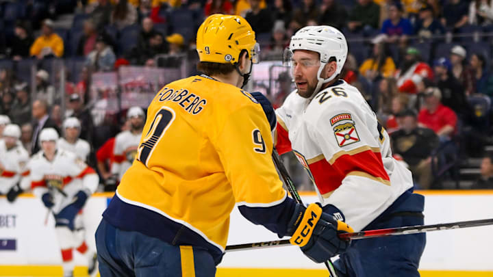 Feb 25, 2025; Nashville, Tennessee, USA;  Florida Panthers defenseman Uvis Balinskis (26) and Nashville Predators left wing Filip Forsberg (9) face off during the third half at Bridgestone Arena. Mandatory Credit: Steve Roberts-Imagn Images
