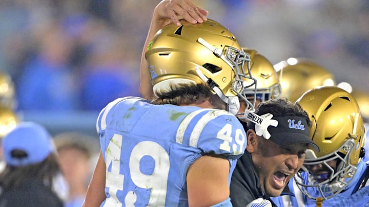 Nov 8, 2024; Pasadena, California, USA;   UCLA Bruins defensive coordinator Ikaika Malloe, center, celebrates with linebacker Carson Schwesinger (49) defensive back Jaylin Davies (6) after an interception in the second half against the Iowa Hawkeyes at the Rose Bowl. Mandatory Credit: Jayne Kamin-Oncea-Imagn Images