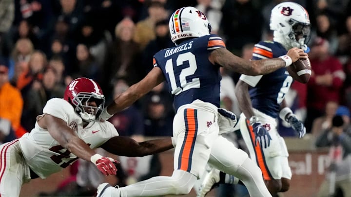 Nov 29, 2025; Auburn, Alabama, USA; Auburn quarterback Ashton Daniels (12) evades a tackle attempt by Alabama linebacker Nikhai Hill-Green (41) to gain a first down at Jordan-Hare Stadium. Mandatory Credit: Gary Cosby Jr.-Tuscaloosa News Nov 29, 2025; Auburn, Alabama, USA; Auburn quarterback Ashton Daniels (12) evades a tackle attempt by Alabama linebacker Nikhai Hill-Green (41) to gain a first down at Jordan-Hare Stadium. Mandatory Credit: Gary Cosby Jr.-Tuscaloosa News