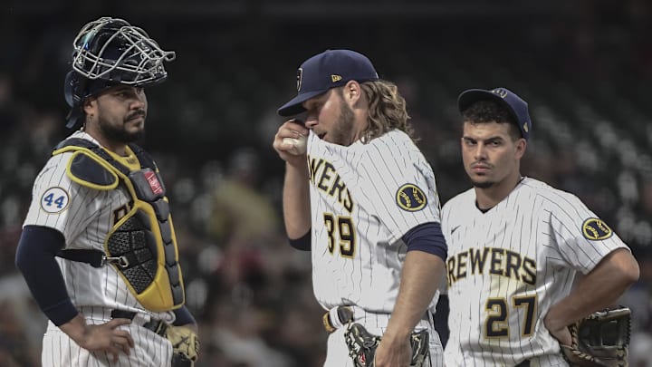 Jun 12, 2021; Milwaukee, Wisconsin, USA; Milwaukee Brewers starting pitcher Corbin Burnes (39) reacts during a pitching change in the fifth inning against the Pittsburgh Pirates as catcher Omar Narvaez (10) and Willy Adames (27) look on at American Family Field. Mandatory Credit: Benny Sieu-Imagn Images