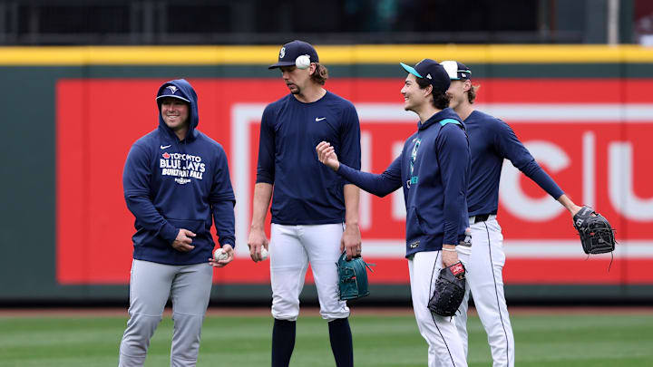 Oct 16, 2025; Seattle, Washington, USA; Toronto Blue Jays infielder Ty France (2) speaks with Seattle Mariners pitcher Logan Gilbert (36), pitcher Bryan Woo (22) and pitcher Bryce Miller (50) during batting practice prior to game four of the ALCS round for the 2025 MLB playoffs at T-Mobile Park. Mandatory Credit: Kevin Ng-Imagn Images